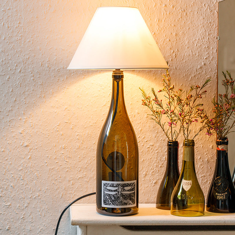 A lamp made from a wine bottle with a cream coloured lampshade